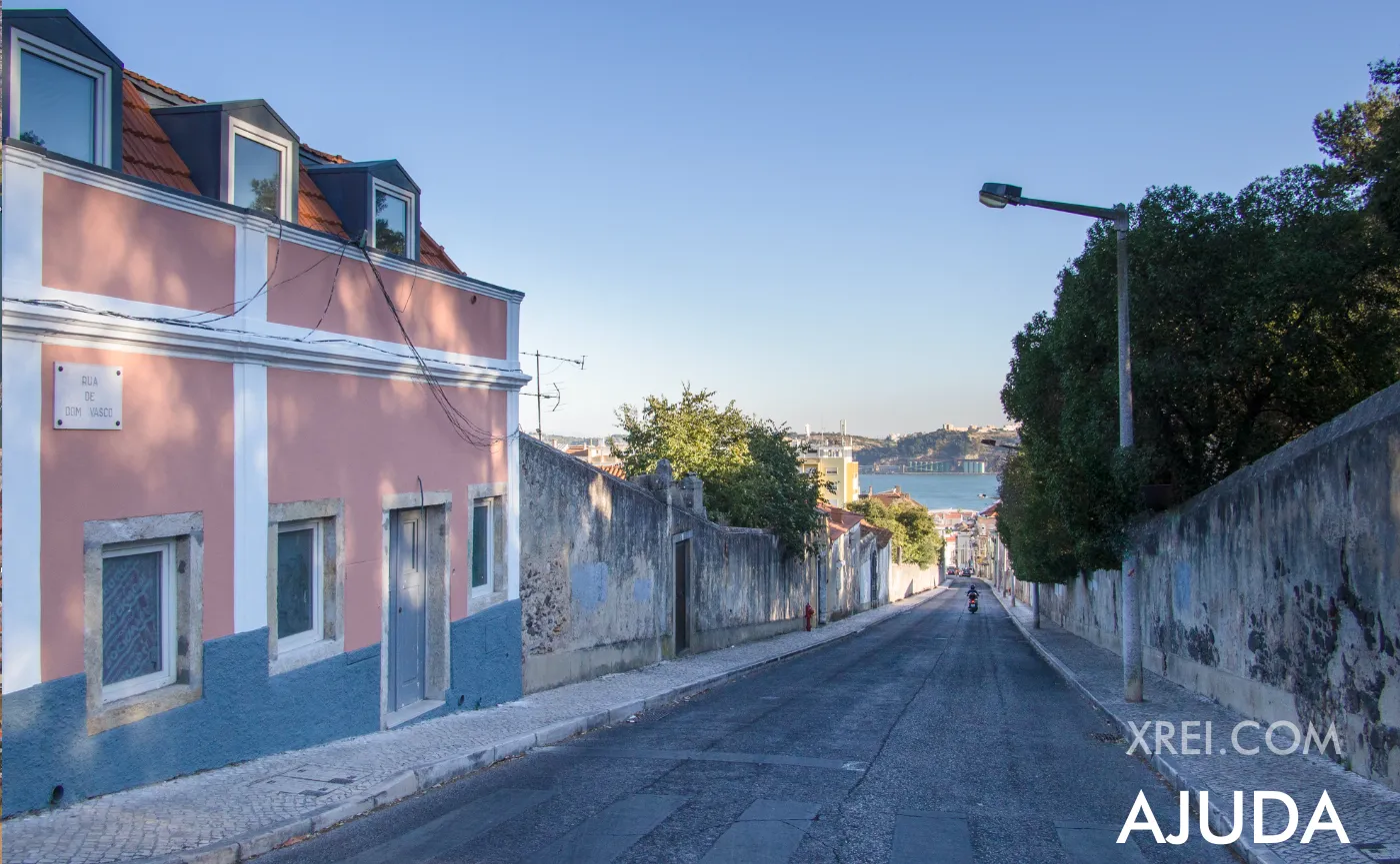 Uma rua típica de Ajuda — paredes de reboco desgastado, fachada rosa tradicional, e o rio enquadrado no fundo da colina.