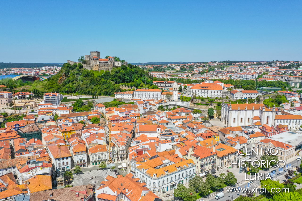 Historic centre of the city of Leiria, with Praça Rodrigues Lobo, the historic buildings surrounding it, the cathedral of Leiria on the right, the municipal stadium of Leiria in the background to the left, and the castle at the top of the image
